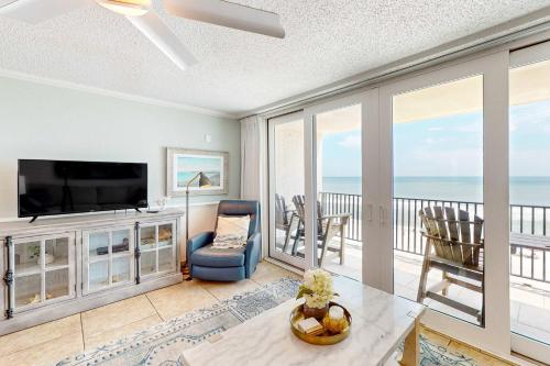a living room with a television and a balcony with the ocean at Gulf-front condo with breathtaking views pool in Orange Beach