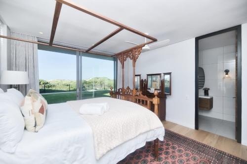 a bedroom with a large white bed and a large window at Sonvanger Villa Struisbaai in Struisbaai