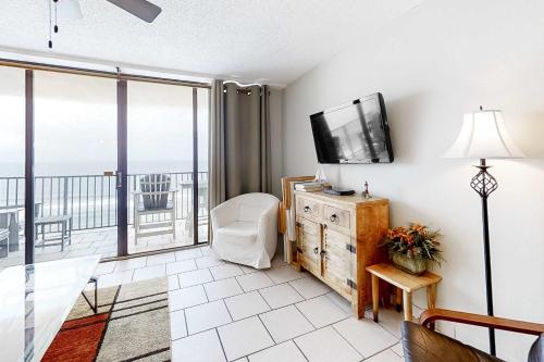 a living room with a television and a balcony at Beachfront Condo with Gulf View Balcony WiFi AC & Shared Pools in Orange Beach