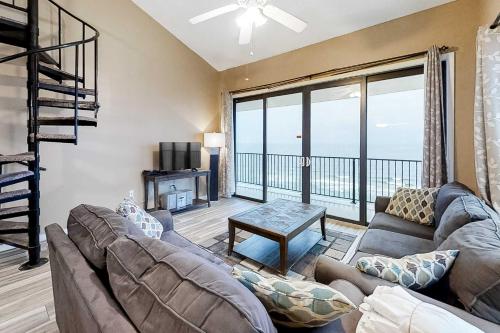 a living room with a couch and a large window at Gulf-front corner condo with wraparound balcony pools beach access in Orange Beach