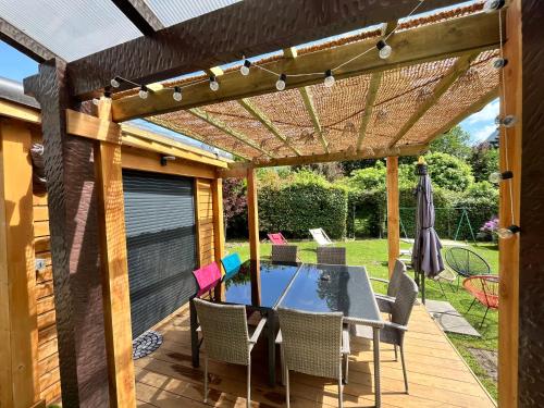 a patio with a table and chairs under a pergola at Le Hourmigué maison 130m2 avec jacuzzi à 15mn de Luchon in Cierp