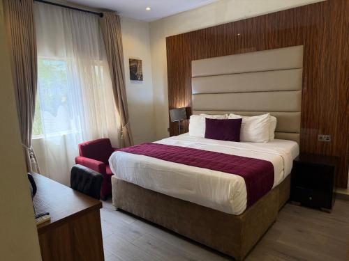 a hotel room with a large bed and a chair at de brit hotel in Benin City