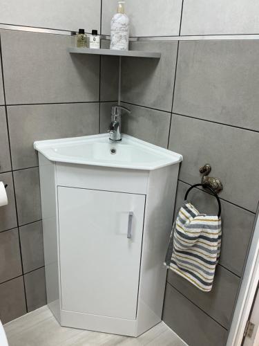 a white bathroom with a sink and a towel at Jayslin in Felpham