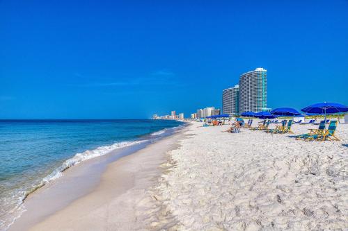 a beach with chairs and umbrellas and the ocean at Tidewater 908 in Orange Beach