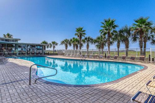 a large swimming pool with chairs and palm trees at Tidewater 908 in Orange Beach