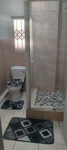 a bathroom with a shower with a toilet and mats at Cozy suburban guest house - Durban in Verulam