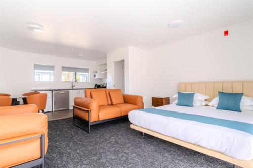 a bedroom with a bed and a couch and a chair at Te Awa Suites in Hamilton