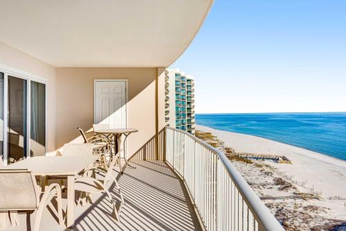 a balcony with tables and chairs and the ocean at Regency Isle 802 in Orange Beach