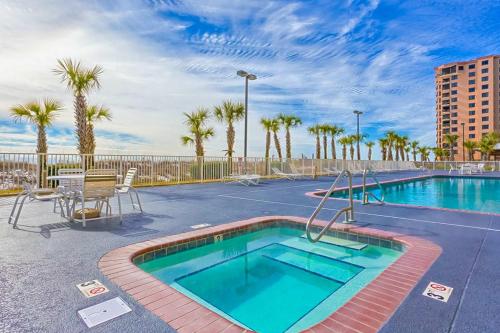 a swimming pool with a tennis court and palm trees at Regency Isle 611 in Orange Beach