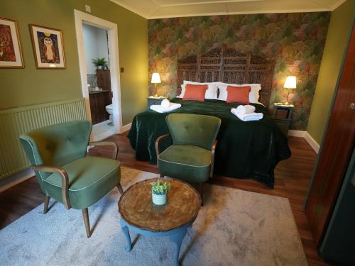 a bedroom with a bed and two chairs and a table at Cruachan B & B in Tomintoul