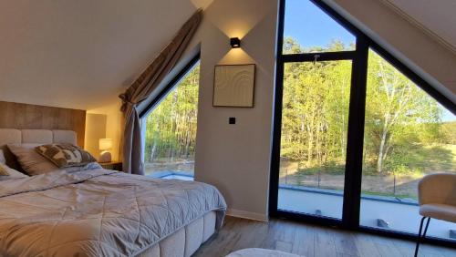 a bedroom with a bed and large windows at Bosarosa Forest & Lake Villa z jacuzzi wanna SPA in Laski Małe
