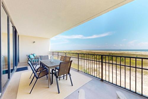 a balcony with a table and chairs and a view of the beach at Beachfront condo with pool private balcony and laundry in Dauphin Island