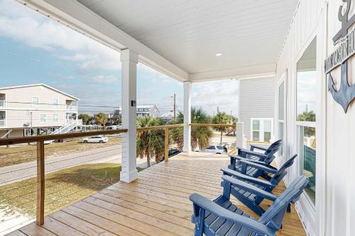 two blue chairs on a porch with a view of the ocean at The Anchor Holds in Dauphin Island