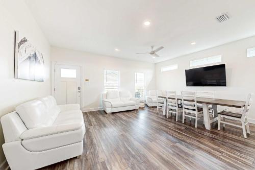 a living room with a dining room table and white chairs at The Anchor Holds in Dauphin Island