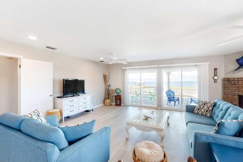 a living room with two blue couches and a television at Little Grand Hotel in Dauphin Island
