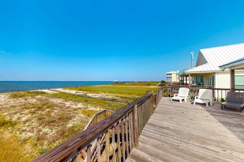 a house with two chairs on a boardwalk next to the ocean at Sunset Beach in Dauphin Island