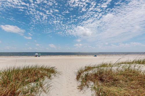 a sandy beach with an umbrella and the ocean at Bale Oasis in Dauphin Island
