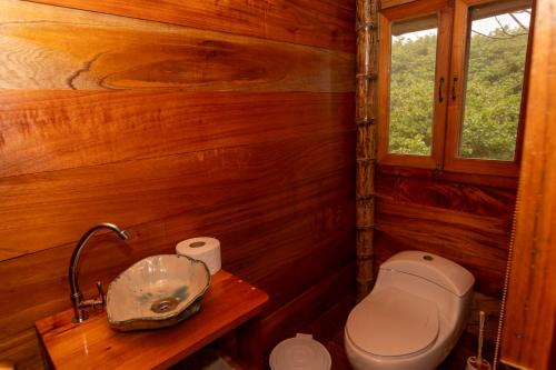 a small bathroom with a toilet and a window at Highland Bamboo Cabin, San Cristóbal Galápagos in San Cristóbal