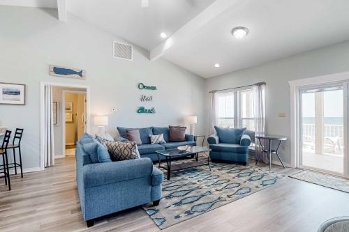 a living room with two blue chairs and a couch at Sea the Gulf in Dauphin Island