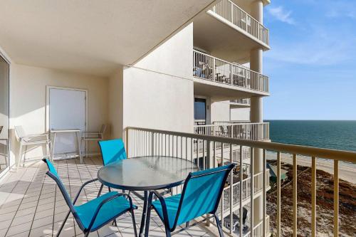 a balcony with a table and chairs and the ocean at Spacious beachfront condo with full kitchen shared pool and beach access in Gulf Shores