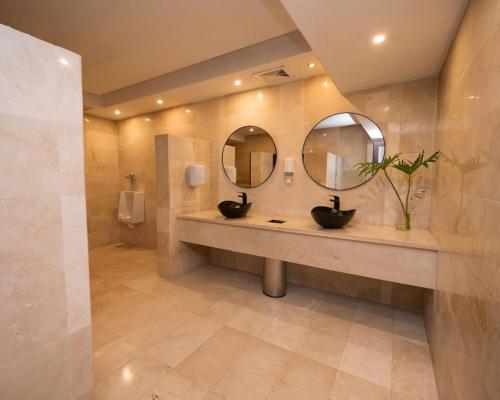a bathroom with two sinks and two mirrors at Caribbean Beachfront Resort in Puerto Plata