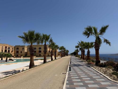 an empty street with palm trees and a building at Fort Chambray Gozo 2BDR Apartment in Għajnsielem