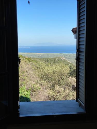 a window in a house looking out at the ocean at Koumara Stone House in Koútsi