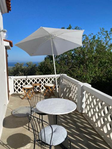 a table and chairs with an umbrella on a balcony at Koumara Stone House in Koútsi