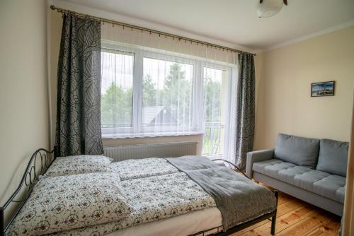 a bedroom with a bed and a window and a couch at ALE WIDOKI Apartamenty Gościnne in Giebło