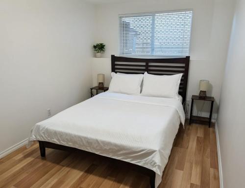 a bedroom with a bed with white sheets and a window at Ashwood monthly in Courtenay
