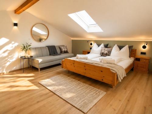 ein Schlafzimmer mit einem Bett, einer Couch und einem Spiegel in der Unterkunft Quartier 27- modern Apartment with Balcony & free parking in Tulfes
