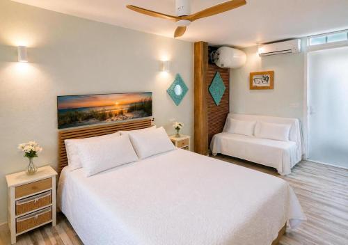 a bedroom with a large white bed and a chair at Estudio con piscina y jardines a 2 min de la playa - Fuengirola in Fuengirola