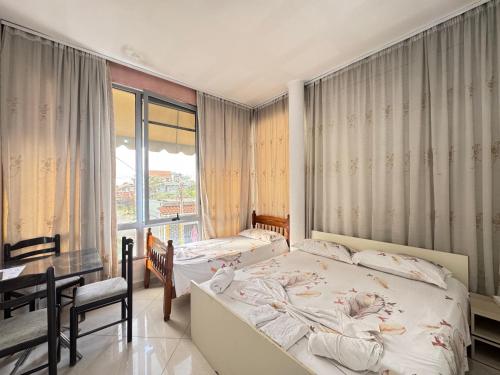 a bedroom with two beds and a desk and a window at Guest House Kasa Garden in Durrës