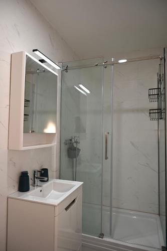 a white bathroom with a shower and a sink at Apartment 84 in Donja Lastva