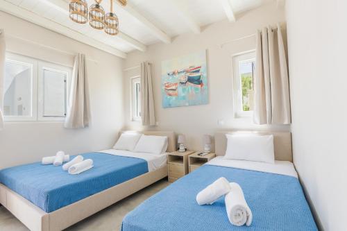 two beds in a room with white and blue at Vivens Mykonos Studios & Suites in Ano Mera