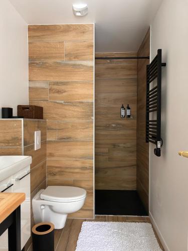 a bathroom with a toilet and a wooden wall at Ker Rev Home Gîte indépendant de charme en longère bretonne in Quimper