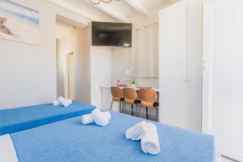 two beds in a room with blue sheets and white towels at Vivens Mykonos Studios & Suites in Ano Mera