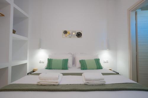 a white bedroom with a large bed with green and white pillows at Vista Mare Suites in Kithnos