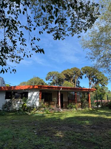 a house in a field with trees in the background at Cumbre Serena by Montea in Empalme