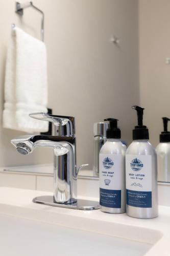 a bathroom sink with two bottles of disinfectants on it at Tofino Resort + Marina in Tofino