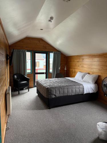 a bedroom with a large bed and a chair at Smoke Lake Hot Springs Lodge & Camp in Rotorua