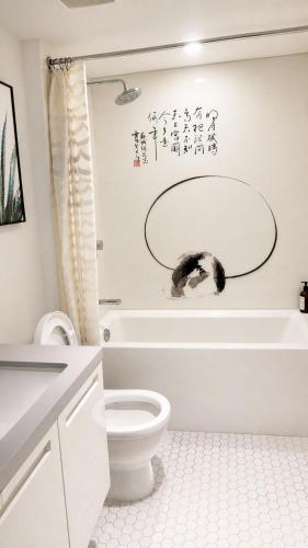 a white bathroom with a toilet and a bath tub at Moden & Cozy Downtown Condo in Vancouver in Vancouver