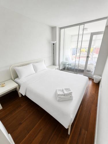 a white bedroom with a large white bed and a window at Moden & Cozy Downtown Condo in Vancouver in Vancouver