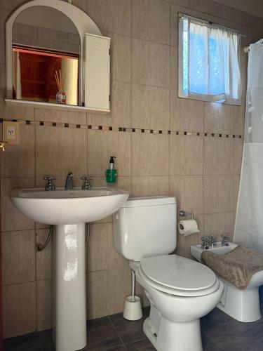a bathroom with a white toilet and a sink at Cabañas Ojo de Agua in Sierra de la Ventana