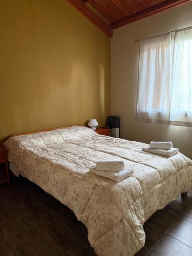 a bedroom with a bed with two towels on it at Cabañas Ojo de Agua in Sierra de la Ventana