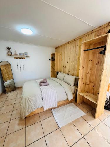 a bedroom with a bed with a wooden wall at De Schelde Beach Cottage in Wilderness