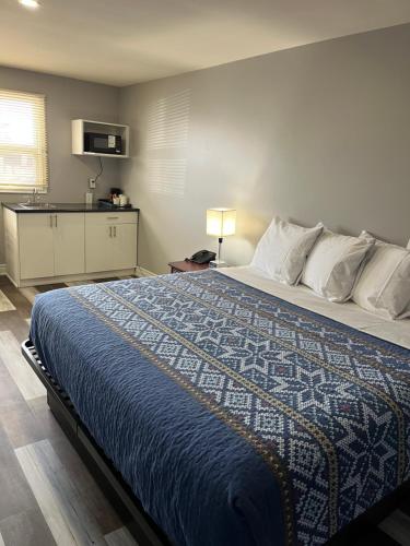 a bedroom with a large bed with a blue blanket at Cobourg Inn in Cobourg