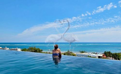 a woman in a infinity pool with a bird in the water at Private Suite, Walk to the Beach, Oceanview Rooftop Pool, WiFi StarLink in Puerto Morelos