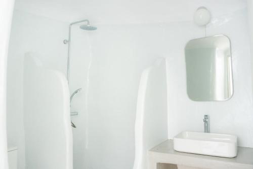 a white bathroom with a sink and a mirror at Thavma Beach House in Mytakas