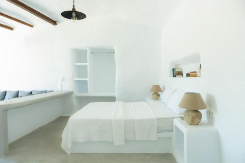 a white bedroom with a bed and a table at Thavma Beach House in Mytakas